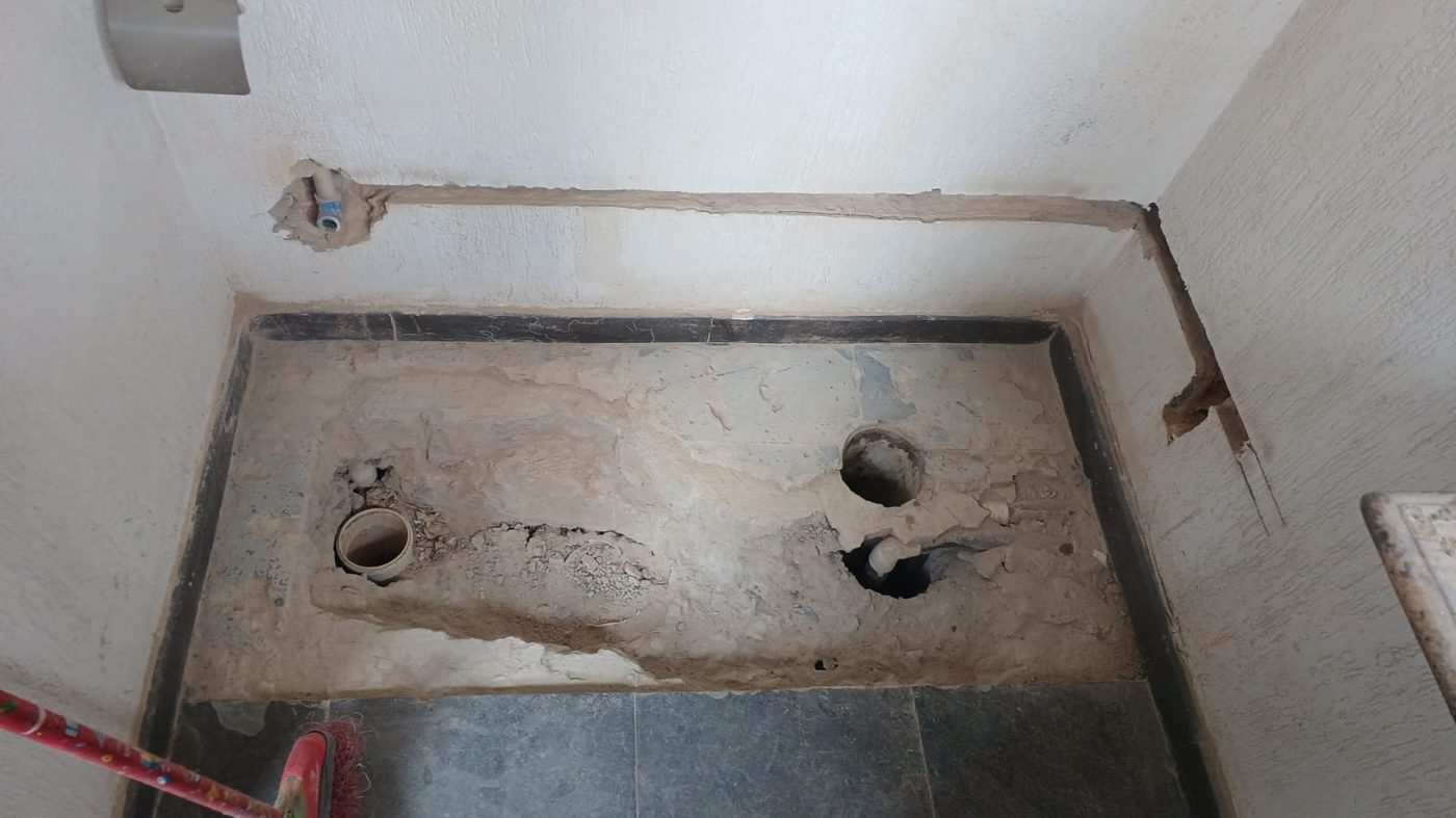 Piso de banheiro aberto com tubulação de esgoto, ralo e pontos de água para reparo hidráulico
